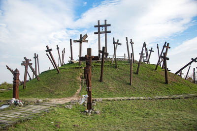 Cross on grass against sky