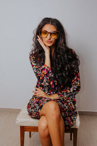 Portrait of smiling young woman sitting against wall