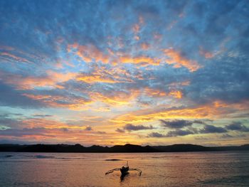 Silhouette person on beach against sky during sunset