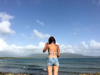 Rear view of young woman standing at beach