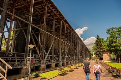 Rear view of people on railway bridge against sky