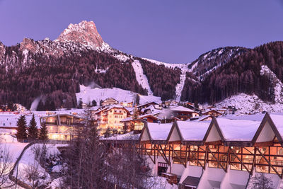 View of selva di val gardena ski resort in italian alps at dusk during winter with ski areas behind