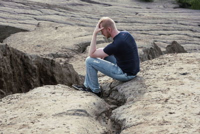 Side view of man sitting on rock