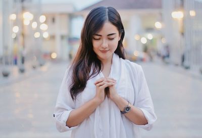 Beautiful young woman standing on street in city