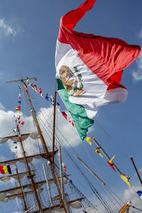 Low angle view of flags hanging on pole against sky