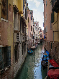 Boats moored in canal amidst buildings against sky