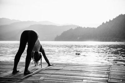 Woman exercising on floorboard at beach