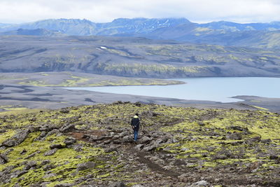 Rear view of man standing on mountain against sky