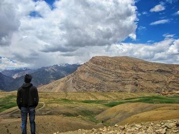 Rear view of man looking at mountains against sky