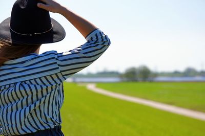 Rear view of woman standing on field against sky