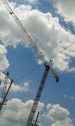 Low angle view of crane against cloudy sky