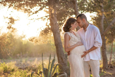 Mid adult couple standing against trees