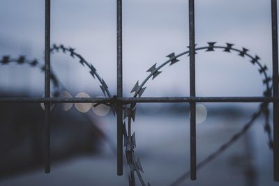 Close-up of barbed wire fence against sky