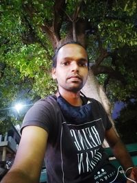 Portrait of young man standing against trees