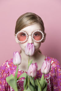 Close up of mod tween girl smelling pink tulips on pink background