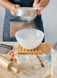 Midsection of woman straining flour in kitchen