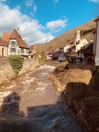 Houses by river against buildings