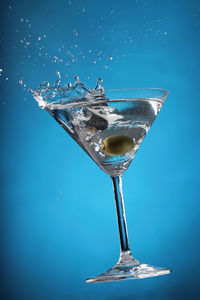 Close-up of cocktail splashing over blue background