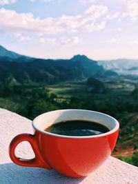 Coffee cup on table against mountains