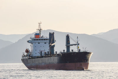 Ship on sea against mountain range