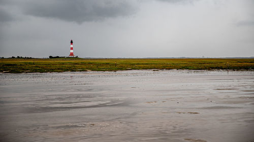 Lighthouse on beach against sky