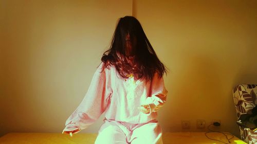 Young woman standing against wall