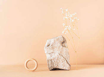 Creative stone podium with  flower and a wooden ring for cosmetics or products on a beige background