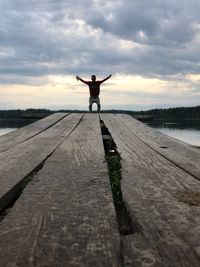 Rear view of person standing on shore against sky