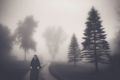 Rear view of woman walking on road in forest