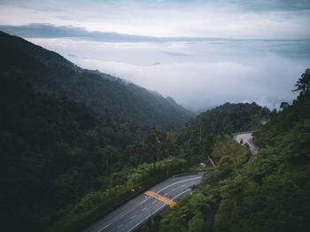 Road amidst trees and mountains against sky