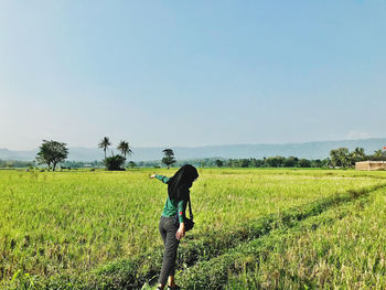 Rear view of man walking on field against sky