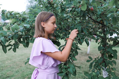 Side view of young woman holding plants