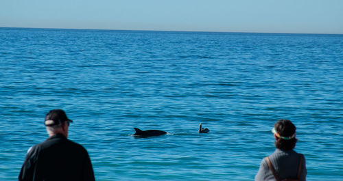 Rear view of man and woman by sea against sky