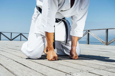 Karate man leaning with clenched fists on wooden platform