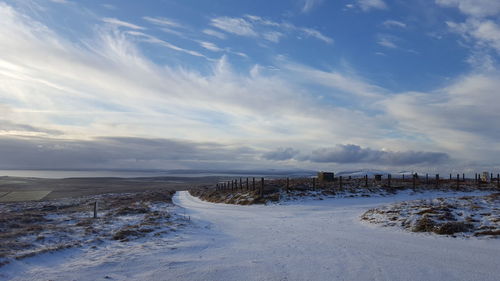 Scenic view of snow covered land against sky