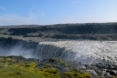 Scenic view of waterfall against sky