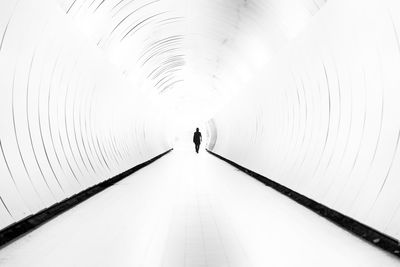 Rear view of woman walking on footpath in tunnel
