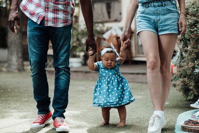 Low section of father and mother walking daughter