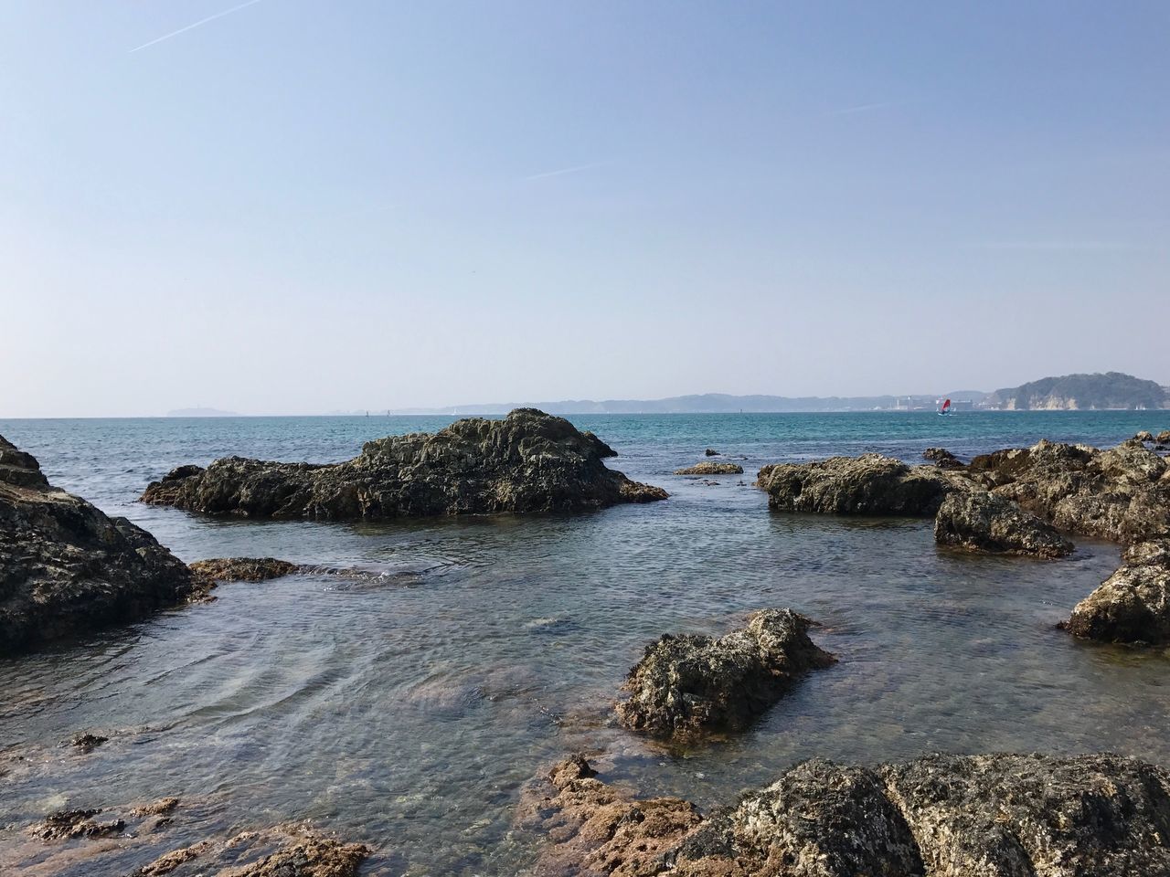 ROCKS ON BEACH AGAINST CLEAR SKY