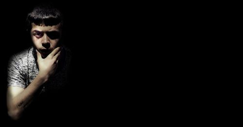 Portrait of young man against black background