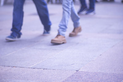 Low section of people walking on tiled floor