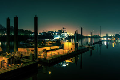 View of factory by river against sky at dusk