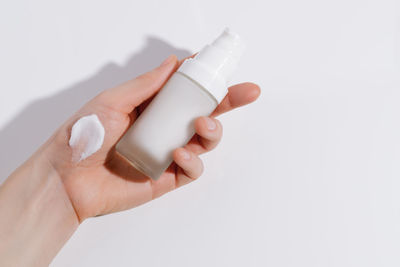 Cropped hand of woman applying nail polish against white background