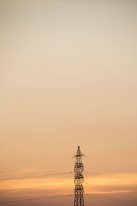 Silhouette electricity pylon against clear sky during sunset