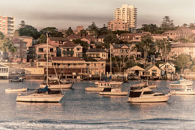 Sailboats moored in sea against buildings in city