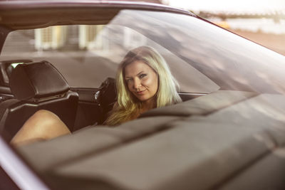 Portrait of beautiful woman sitting at car