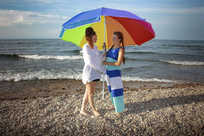 Rear view of woman with umbrella standing at beach