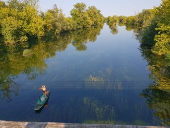 Reflection of man in lake against trees