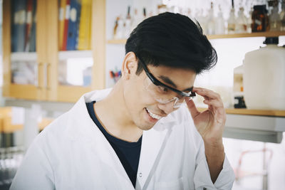 Confident young male student wearing protective eyewear in chemistry laboratory