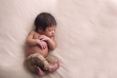 High angle view of cute newborn sleeping on bed at home